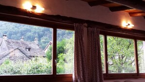 Ein Zimmer mit großem Fenster, Holzbalken und einem Vorhang.