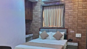 Ein Schlafzimmer mit einem Bett, einem Deckenventilator, einem Nachttisch und einem Fenster mit Vorhängen.