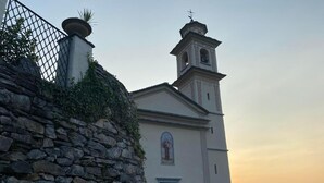 Una chiesa con un campanile, un muro di pietra e cielo sereno.