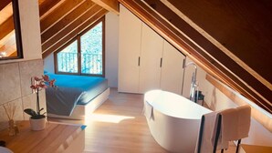 Una camera da letto moderna con un lucernario, una vasca da bagno grande e un soffitto in legno.