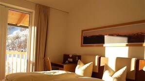 A hotel room with a bed, a nightstand, a painting on the wall, and a window with curtains. - Panorama Ischgl in Kappl by Interhome (Kappl)