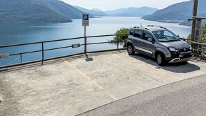 A parking area with a car, a private parking sign, and a sign indicating a house named 'Casa Surpresa.' - Casa Ninfea by Interhome (Brissago)