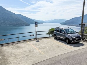 A parking area with a car, a private parking sign, and a sign indicating a house named 'Casa Surpresa.' - Casa Ninfea by Interhome (Brissago)
