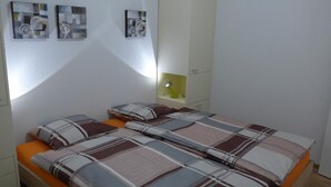 A bedroom with a bed, a nightstand, a lamp, and three wall-mounted artworks. - Casa Ninfea by Interhome (Brissago)