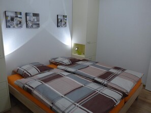 A bedroom with a bed, a nightstand, a lamp, and three wall-mounted artworks. - Casa Ninfea by Interhome (Brissago)