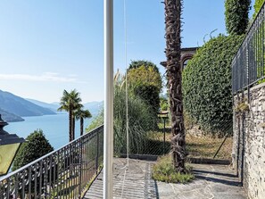 Una escalera conduce a una terraza con vistas a un lago, bajo un cielo despejado y montañas distantes.