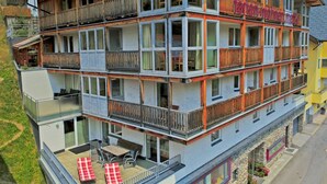 Een meerlaags hotel met balkons, een terras met zitplaatsen buiten, en een bordje dat aangeeft dat het een vrouwenhostel is.