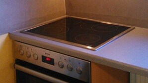 A kitchen with a built-in stovetop and oven, a digital clock displaying 6:44, and a vent hood above the stovetop. - Wohnung in Altengroden mit Garten by Interhome (Wilhelmshaven)