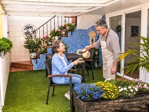 A person pouring a drink into a cup, seated at a table with a potted plant beside them. - Apartment El Hierro by Interhome (El Paso)