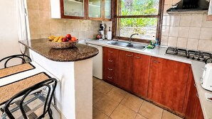 A compact kitchen with a built-in island, a sink, and a window with a view of greenery. - La Gomera by Interhome (El Paso)