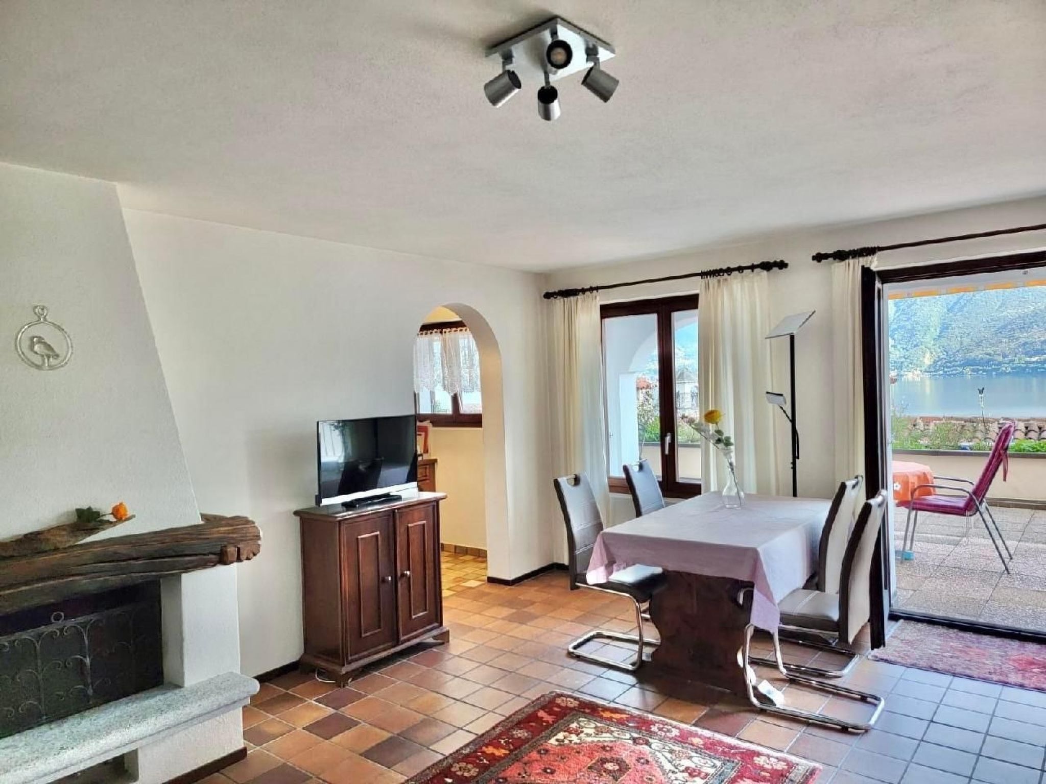 Ein Wohnzimmer mit Fernseher, Kamin, Esstisch, Stühlen und Seeblick.
