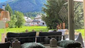 A room with a view of a mountain and a green field. There are two sofas and a table with cushions. - Chesa Ladina by Interhome (La Punt-Chamues-ch)