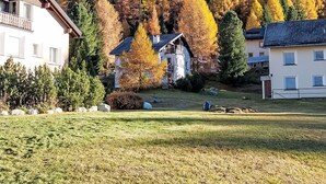 A residential area with houses, a grassy lawn, and trees with autumn foliage.