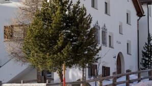 Un bâtiment blanc, avec une clôture en bois et de la neige au sol.