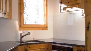 Une cuisine avec des meubles de rangement en bois, un plan de travail noir, une fenêtre et un lave-vaisselle encastré.