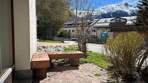 Un banc de pierre se trouve devant un bâtiment, avec une montagne enneigée en arrière-plan.