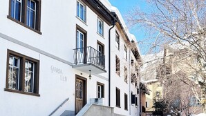 A building named 'Gvarda Len' with a staircase leading to the entrance, a balcony, and a snow-covered street. - Chesa Maura by Interhome (Celerina)
