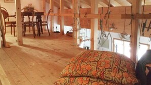 A wooden interior with exposed beams, a dining table, chairs, and a patterned cushion. - Chesa Maura by Interhome (Celerina)