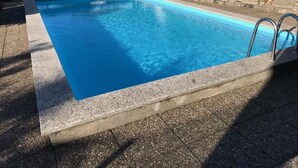 A rectangular swimming pool with a concrete edge and a metal ladder on one side. - Piazzogna by Interhome (Piazzogna)