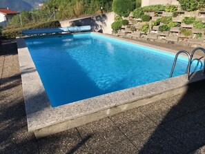 A rectangular swimming pool with a concrete edge and a metal ladder on one side. - Piazzogna by Interhome (Piazzogna)