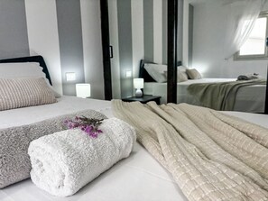 Een hotelkamer met twee bedden, gestreepte wanden, een spiegel en een raam.