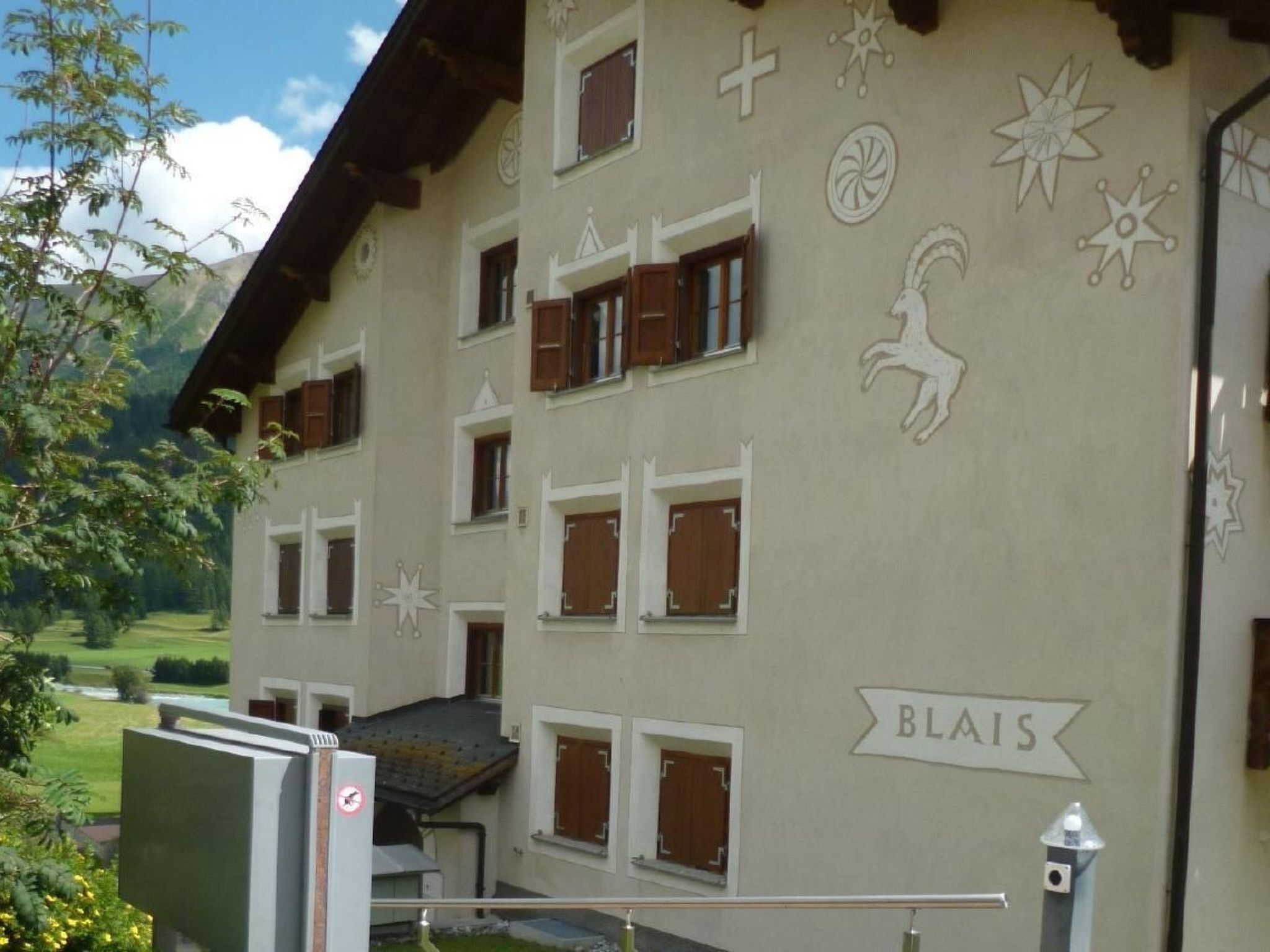 Ein Gebäude mit vielen Fenstern, von denen einige mit Fensterläden versehen sind, und einem Schild mit der Aufschrift 'BLAIS' an der Seite.