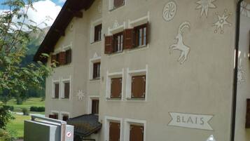 Ein Gebäude mit vielen Fenstern, von denen einige mit Fensterläden versehen sind, und einem Schild mit der Aufschrift 'BLAIS' an der Seite.
