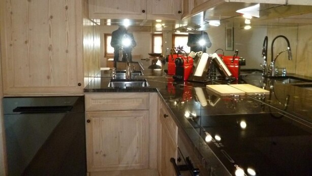 A kitchen with wooden cabinets, a black countertop, and stainless steel appliances. - Chesa Blais by Interhome (Zuoz)