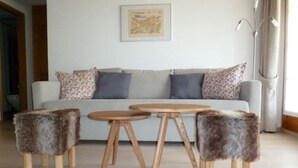 A living room with a sofa, two round wooden tables, and three furry stools. - Chesa Blais by Interhome (Zuoz)
