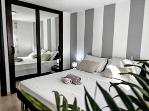 Una camera d'albergo con un letto, comodini, uno specchio e vista attraverso una porta scorrevole.
