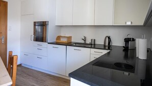 Een moderne keuken met witte kasten, een zwart aanrecht en een ingebouwde kookplaat.