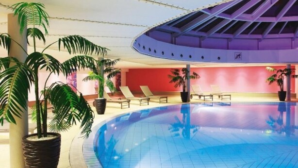 Une piscine avec des chaises longues et des plantes en pot.