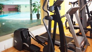 Une salle de sport équipée de tapis de course, d’un vélo elliptique et d’un rameur.