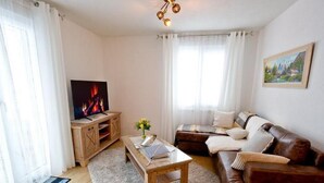 Een woonkamer met een tv-meubel van hout, een bank, een salontafel en een schilderij aan de muur.