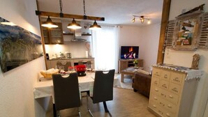 Een gezellige woonkamer met een eethoek, een televisie en een houten kast met lades.