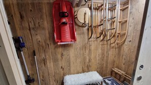 Een houten kamer met een rode kajak, een bank en een houten wandrek met ski’s en stokken.