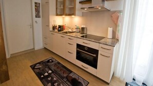 Een kleine keuken met een inbouwoven, een spoelbak en een aanrecht met diverse apparaten.