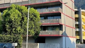 A multi-story building with balconies, a parking area, and a tree in front. - Wohnung Orizia by Interhome (Locarno)