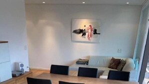 A modern dining area with a wooden table and black chairs, a coffee machine, and a painting on the wall. - Wohnung Orizia by Interhome (Locarno)