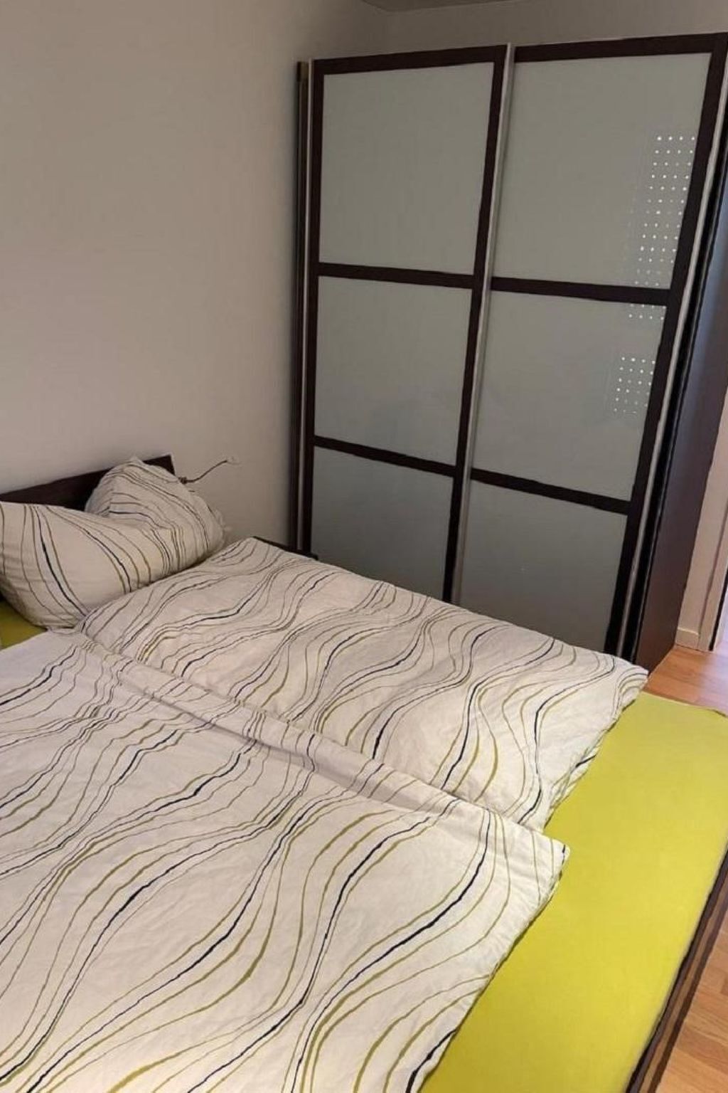 A bed with a striped bedspread and a yellow mattress cover.