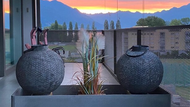 A balcony with two large vases, a view of mountains, and a sunset. - Wohnung Orizia by Interhome (Locarno)
