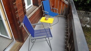 A wooden deck with two blue chairs and a yellow table. - Des Alpes 4-Bettwohnung by Interhome (Hasliberg)