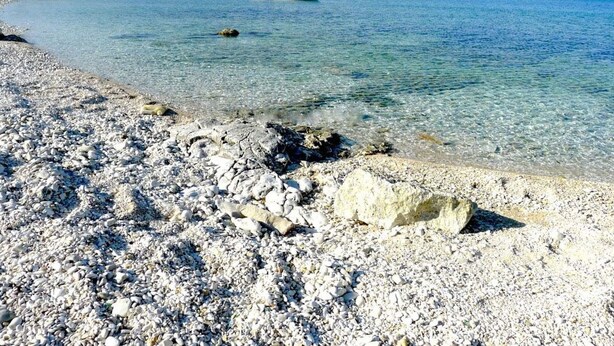 A pebble beach with clear water and a boat in the distance. - mit Blick auf das Wasser by Interhome (Medulin/Ližnjan)
