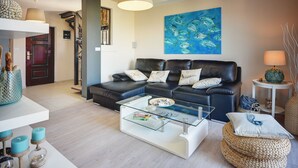 A modern living room with a glass coffee table, a black leather sofa, and a painting of fish on the wall. - mit Blick auf das Wasser by Interhome (Medulin/Ližnjan)