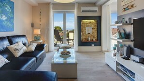 A modern living room with a black leather sofa, a glass coffee table, a stone fireplace, and a TV stand. - mit Blick auf das Wasser by Interhome (Medulin/Ližnjan)