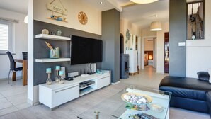 A modern living room with a flat-screen TV, white entertainment unit, glass coffee table, and a black leather sofa. - mit Blick auf das Wasser by Interhome (Medulin/Ližnjan)