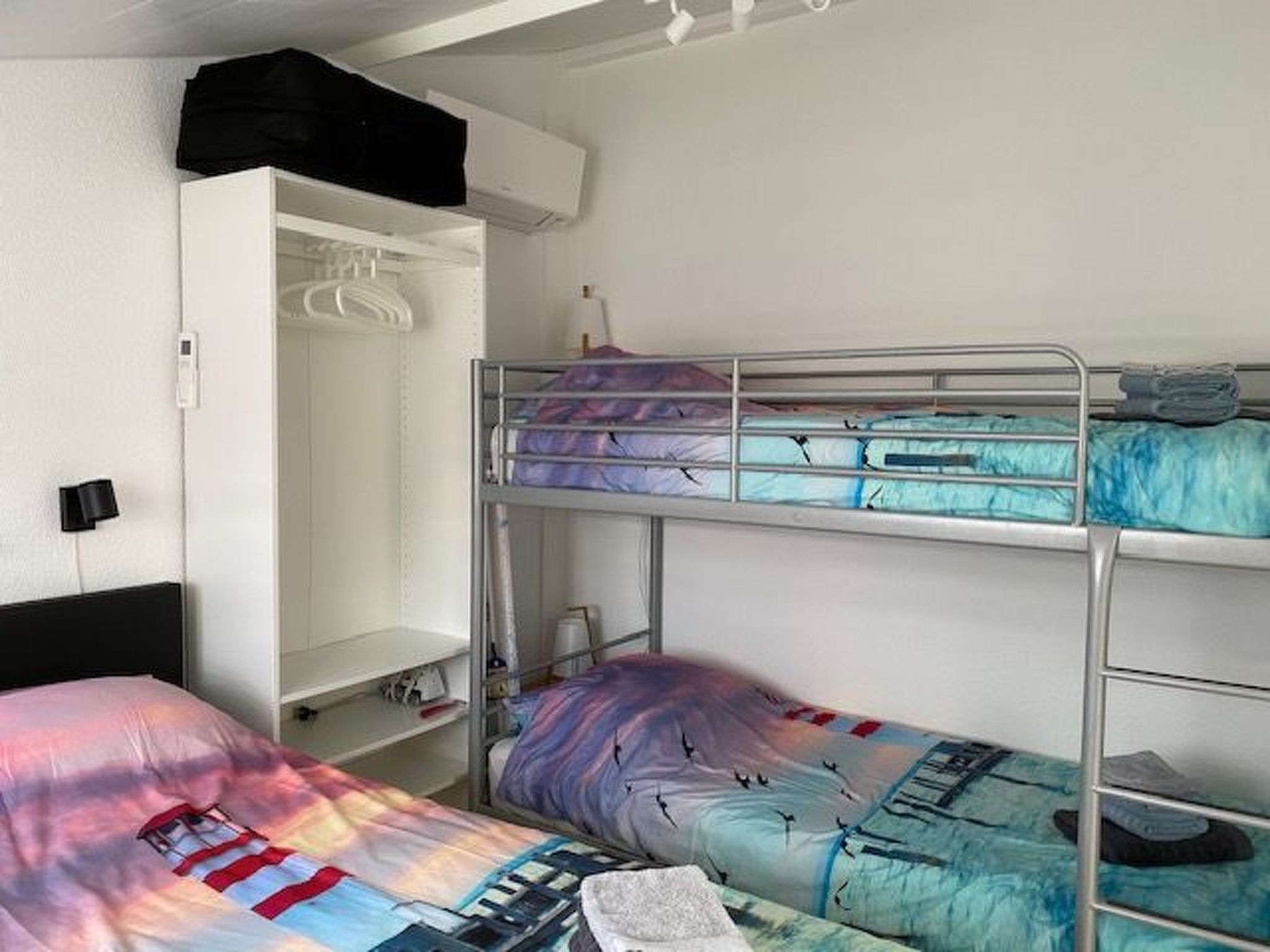 Dormitorio con literas, un armario blanco y un escritorio.