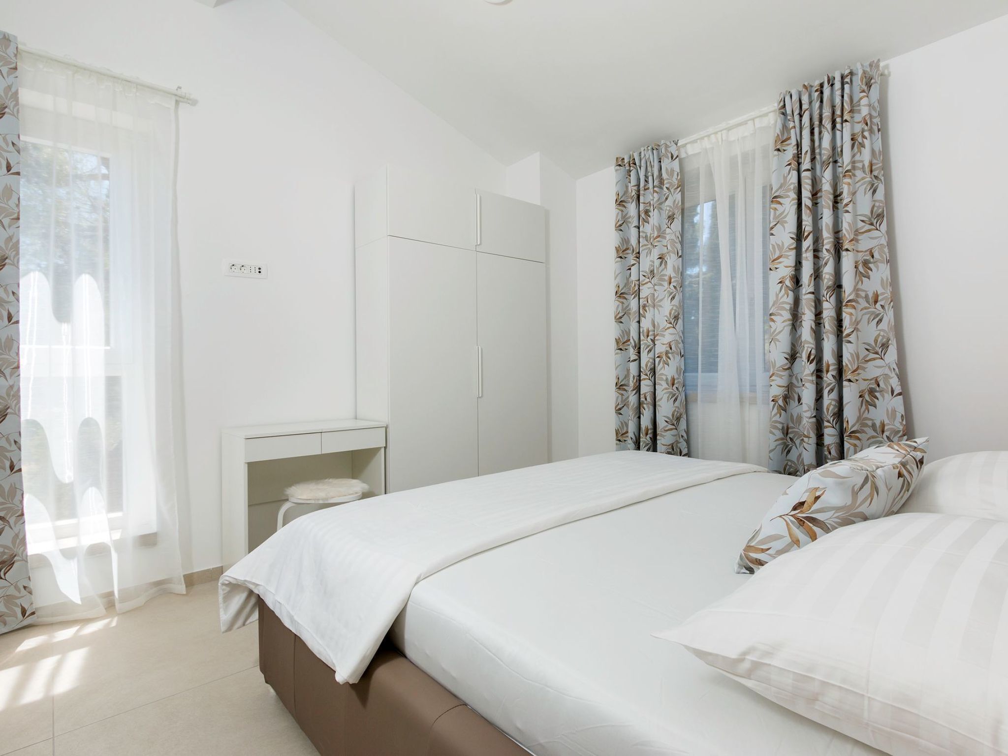 A bedroom with a bed, a desk, and a wardrobe.