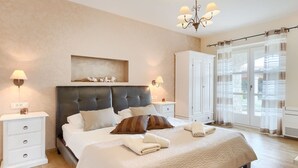 Une chambre à coucher avec un grand lit, deux tables de chevet, une armoire et un lustre.