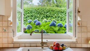 Une cuisine avec une fenêtre, un évier et un panier de fruits sur le plan de travail.